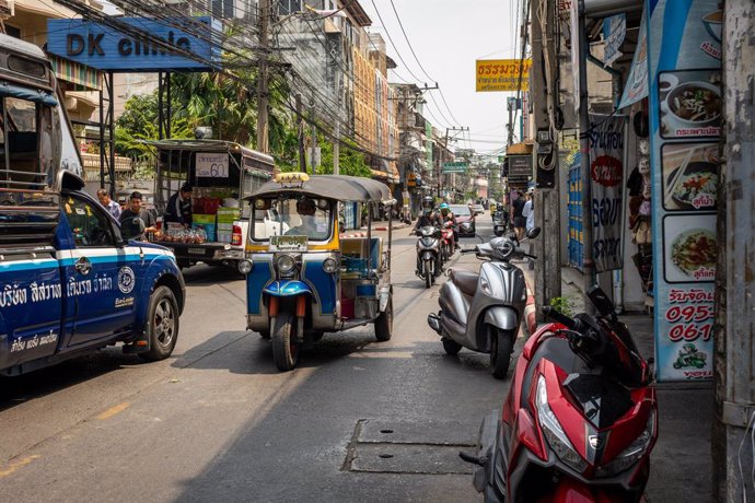 February 22, 2025, Samut Prakan, Thailand: A view of a narrow street with a truck, tuk-tuk, and motorcycles parked near local shops, at Samrong Market. The Yellow Line Monorail has improved mobility and provided an alternative to road travel, connecting B