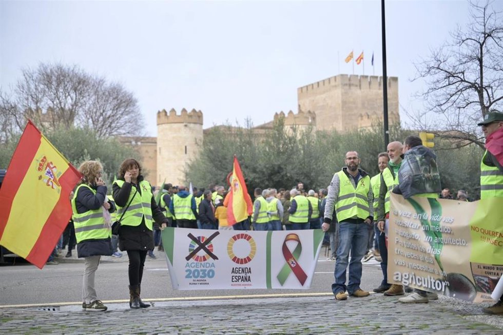 Agricultores y ganaderos frente al palacio de la Aljafería al comienzo del acto de protesta de este jueves en Zaragoza.