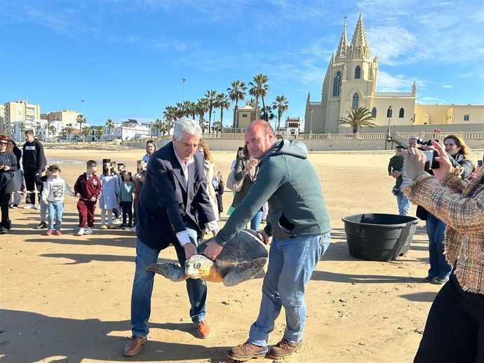 Oscar Curtido y el alcalde de Chipiona liberando una de las tortugas en la playa de Regla.