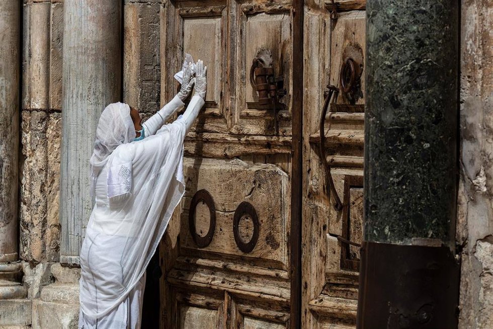 Archivo - Una mujer reza frente a las puertas cerradas de la Iglesia del Santo Sepulcro en Jerusalén (archivo)