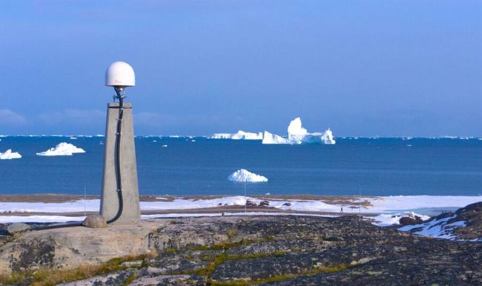 As alterações na elevação do solo são medidas por sistemas globais de navegação por satélite (GNSS). Essa estação GNSS com icebergs ao fundo está localizada na Groenlândia.