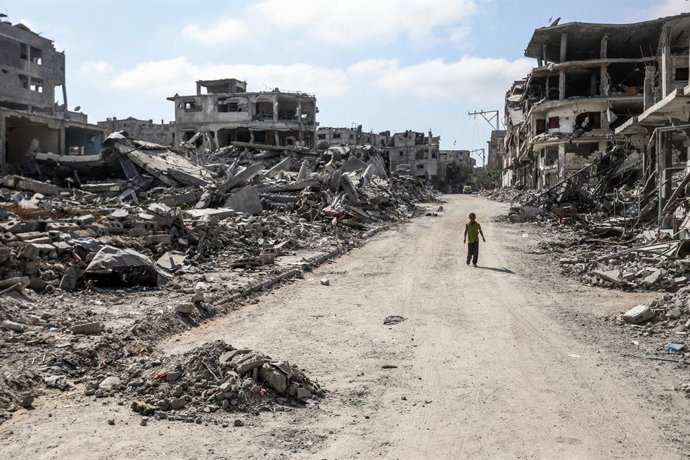 Archivo - Arquivo - Um menino palestino passa por prédios destruídos por ataques do exército israelense na cidade de Khan Younis, no sul da Faixa de Gaza (arquivo).