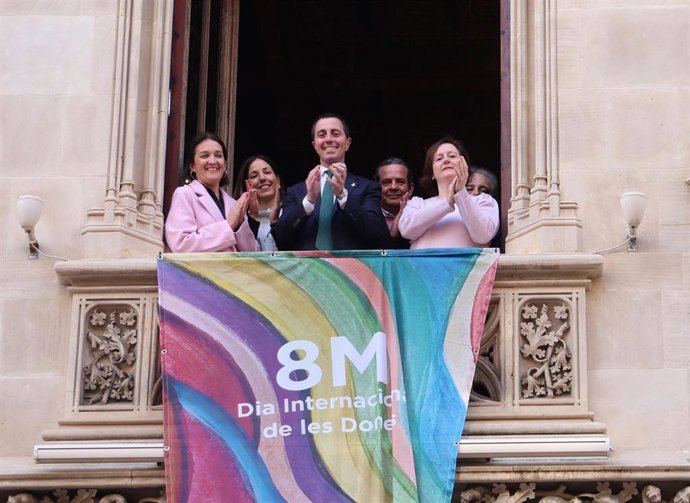 La directora del IbDona, Catalina Salom, el presidente del Consell de Mallorca, Llorenç Galmés, y la directora insular de Familias, Ana Ferriol, entre otras autoridades, despliegan la banderola conmemorativa del 8M.