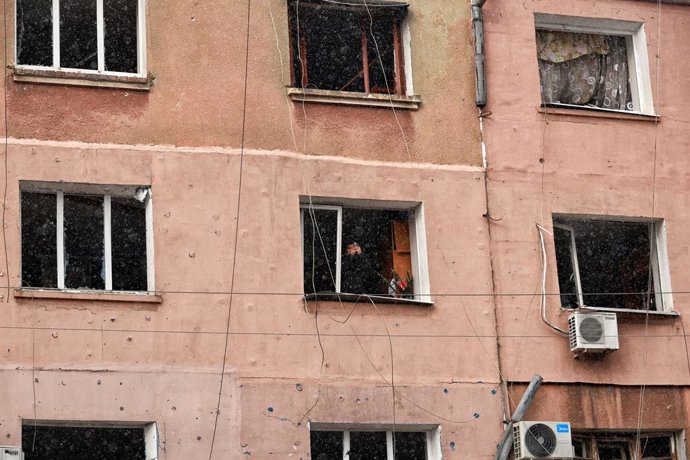 20 de fevereiro de 2025, Odesa, Ucrânia: ODESA, UCRÂNIA - 20 DE FEVEREIRO DE 2025 - Uma mulher tira uma foto em um prédio residencial danificado por um ataque de drone russo, em Odesa, no sul da Ucrânia.