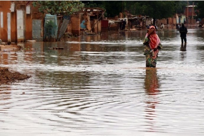 Una mujer vadea una calle inundada en Niamey, la capital de Níger, uno de los países analizados como bajo alta Vulnerabilidad ante el cambio climático en el informe A Gathering Storm Plan International.