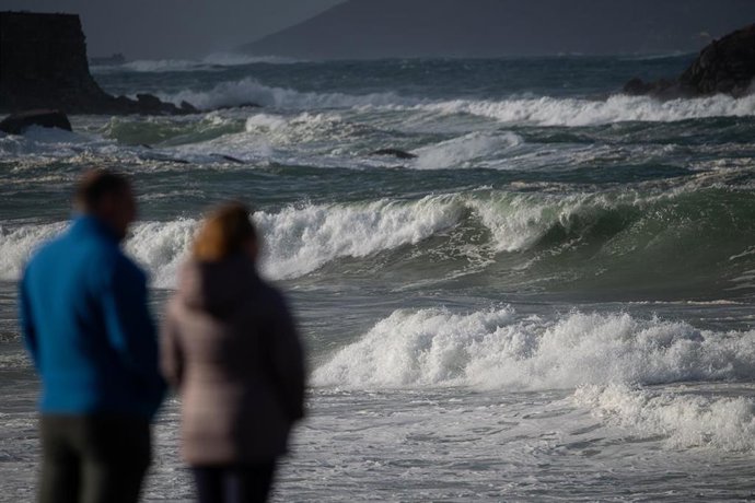 Archivo - Dos personas observan el mar con olas por un temporal, en una imagen de archivo. 