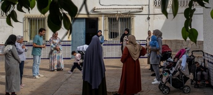 Un grupo de personas migrantes conversa en el patio de una vivienda en Almería.