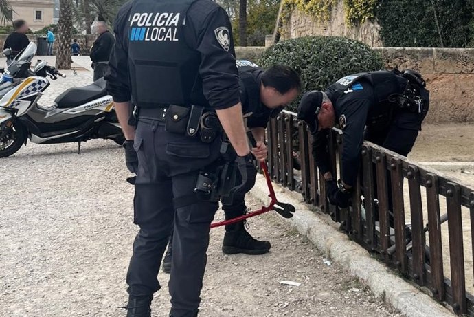 Agentes de la Policía Local de Palma retiran uno de los patinetes atados al vallado del parque infantil de Dalt Murada.