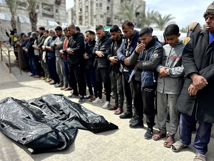Palestinos ao lado dos corpos de duas pessoas mortas em um bombardeio israelense na Faixa de Gaza (arquivo)