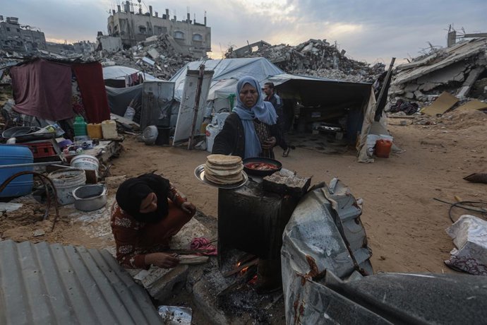 3 de março de 2025, ?Beit Lahia, Faixa de Gaza, Território Palestino: O palestino Karam Abu Haloub e sua esposa Faten preparam comida para o iftar durante o terceiro dia do mês sagrado do Ramadã em uma tenda que montaram nas ruínas de sua casa destruída e