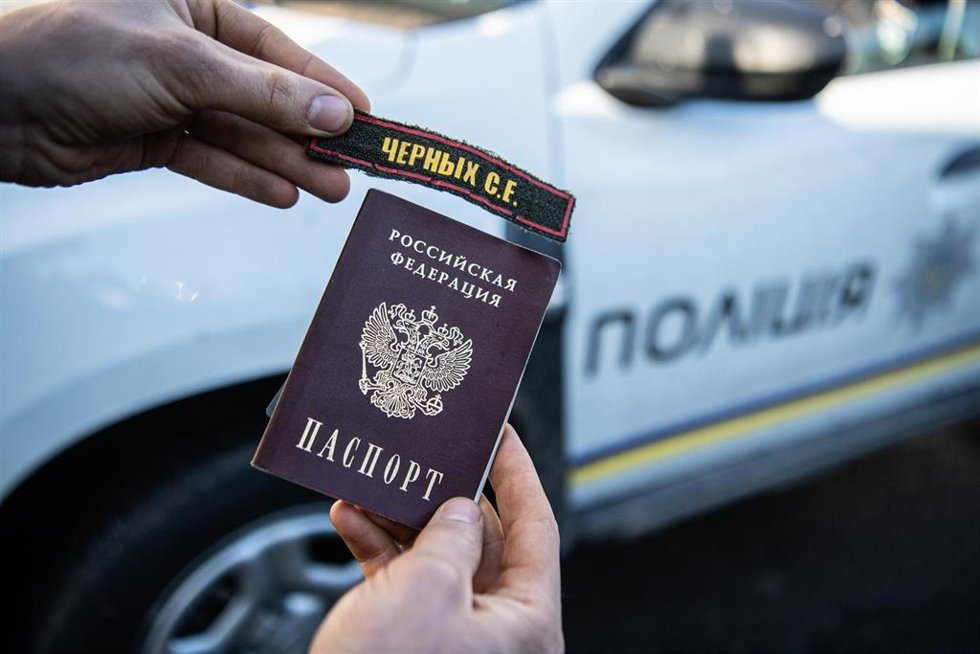 Archivo - Un hombre con un pasaporte y un parche rusos (Archivo)