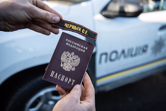 Archivo - April 8, 2022, Borodyanka, Kyiv Oblast, Ukraine: A man holds a passport and patch that local police claimed to belong to a Russian solder in Bucha, a town outside Kyiv that was recently liberated from Russian occupation.