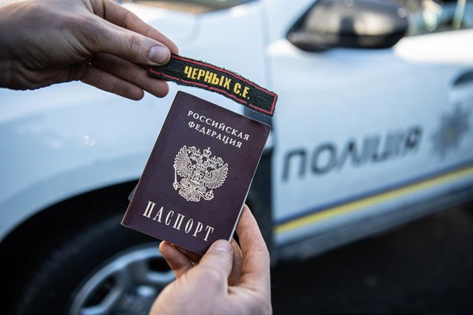 Archivo - Arquivo - 8 de abril de 2022, Borodyanka, Oblast de Kiev, Ucrânia: Um homem segura um passaporte e um adesivo que a polícia local afirma pertencer a um soldado russo em Bucha, uma cidade nos arredores de Kiev que foi recentemente libertada da oc