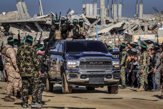 15 February 2025, Palestinian Territories, Khan Younis: Fighters of the Islamic Jihad and Ezz al-Din Al-Qassam brigades, the military wing of Hamas, arrive to hand over three Israeli hostages to representatives of the Red Cross in the southern Gaza Strip 