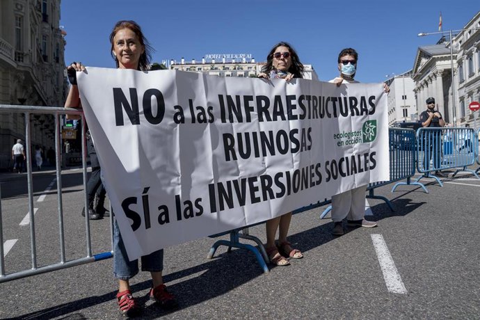 Archivo - Tres personas sostienen una pancarta con el logo de Ecologistas en acción y donde se lee "No a las infraestructuras ruinosas, sí a las inversiones sociales", en una concentración contra la ampliación del aeropuerto Adolfo Suárez Madrid-Barajas, 