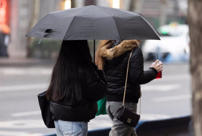 Archivo - Personas con paraguas bajo la lluvia durante la llegada de la borrasca ‘Garoé’, a 20 de enero de 2025, en Madrid (España).