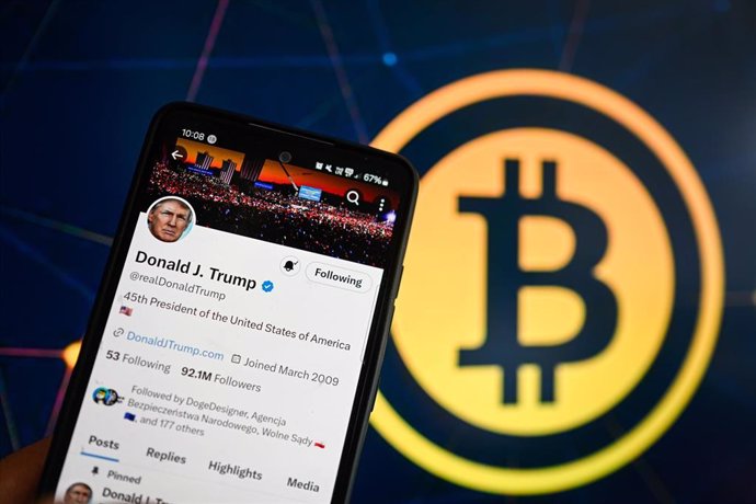 Archivo - Imagen de archivo de una publicación del presidente de EEUU, Donald Trump, en la red social X con un logo de bitcoin al fondo