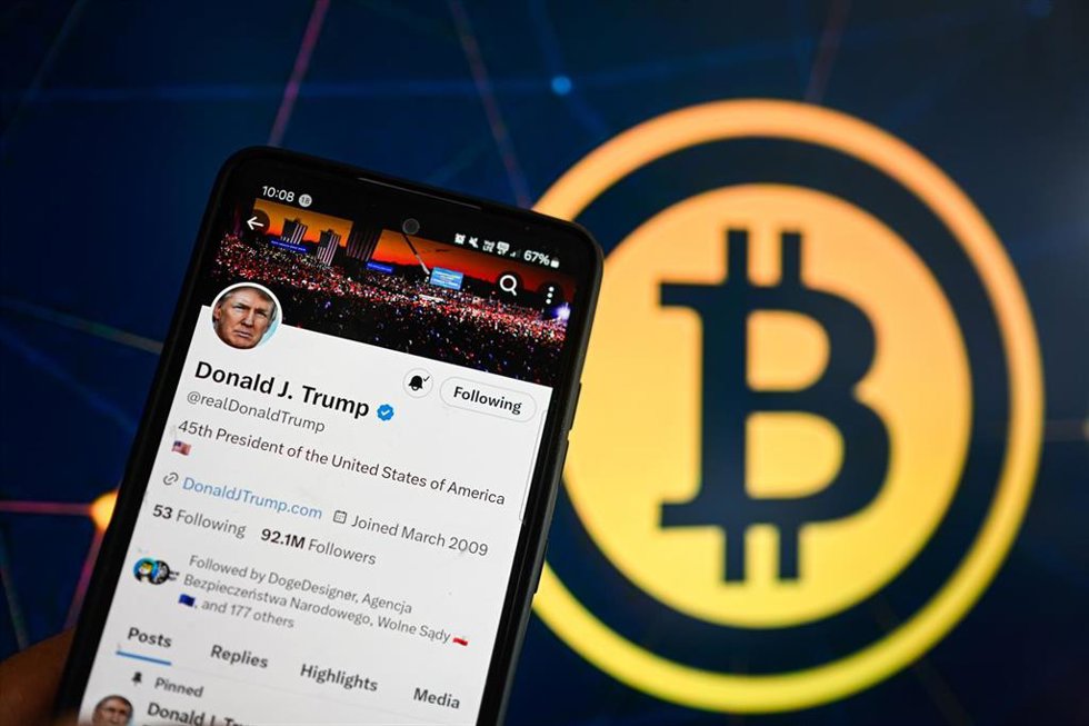 Archivo - Imagen de archivo de una publicación del presidente de EEUU, Donald Trump, en la red social X con un logo de bitcoin al fondo