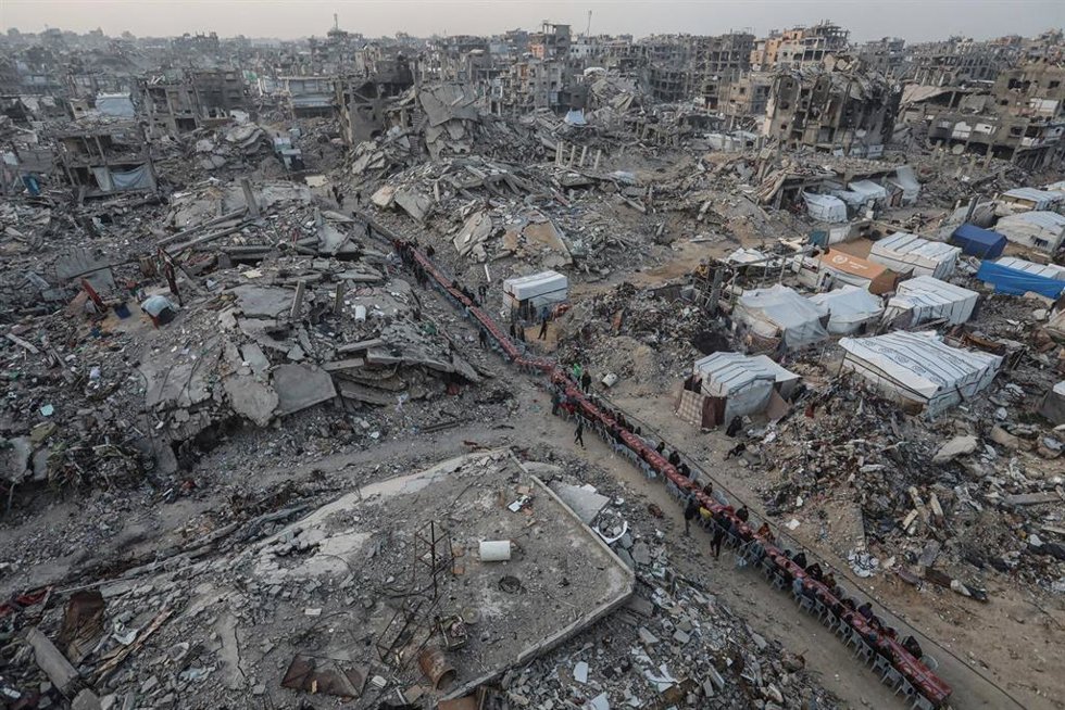 Palestinos se reúnen entre edificios destruidos para romper el ayuno juntos durante el mes sagrado de Ramadán en el campamento de refugiados de Yabalia, en el norte de la Franja de Gaza