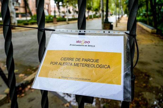 Archivo - Cartel en una reja de entrada al Parque de María Luisa de Sevilla que indica el cierre por alerta meteorológica, en una imagen de archivo