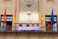 La pancarta del Día Internacional de la Mujer luce en el balcón principal del Ayuntamiento de Zaragoza