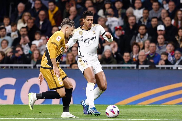 Archivo - El jugador del Real Madrid Jude Bellingham intenta regatear al lateral rumano del Rayo Vallecano Andrei Ratiu, en un partido de LaLiga EA Sports 2023-2024.