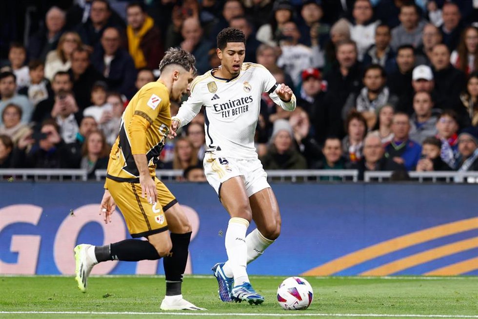 Archivo - El jugador del Real Madrid Jude Bellingham intenta regatear al lateral rumano del Rayo Vallecano Andrei Ratiu, en un partido de LaLiga EA Sports 2023-2024.