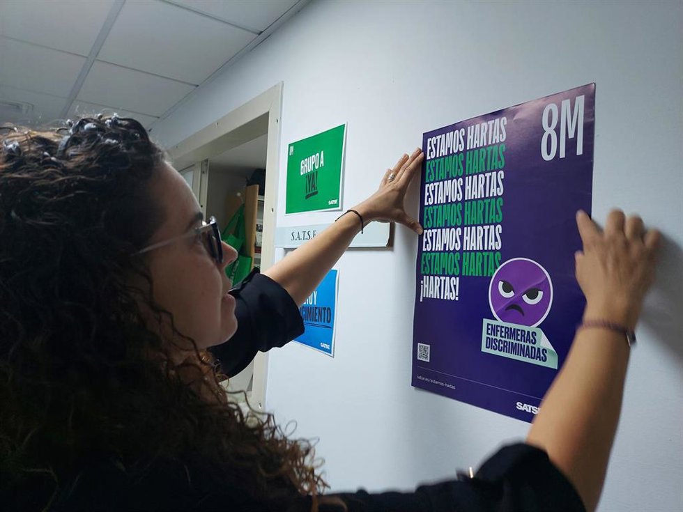 Archivo - Una enfermera cuelga un cartel de la campaña del sindicato SATSE con motivo del Día Internacional de la Mujer (archivo)