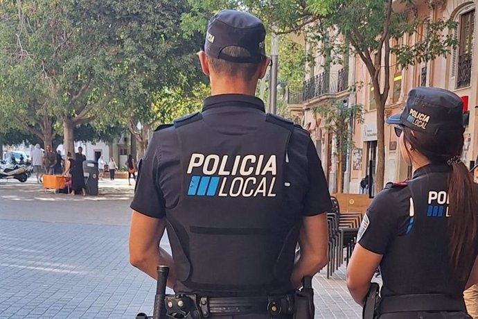 Dos agentes de la Policía Local, de espaldas, en la plaza de España de Palma