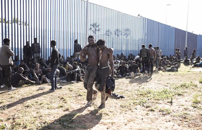 Archivo - Grupo de migrantes junto a una valla fronteriza.