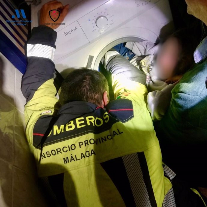 Efectivos del Consorcio Provincial de Bomberos de Málaga liberan a una niña de ocho años que había quedado atrapada con las pieernas en el interior de una lavadora.