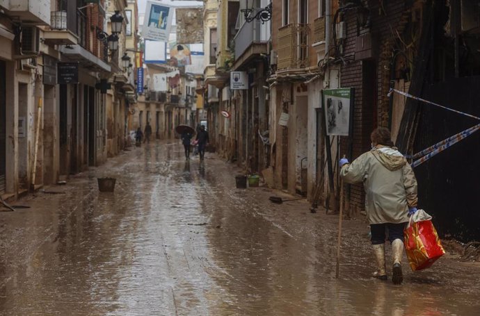 Archivo - Una mujer pasea por la calle anegada de barro, a 13 de noviembre de 2024, en Paiporta, Valencia
