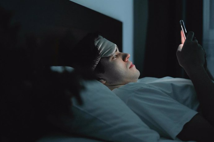 Usuário usando um smartphone na cama.