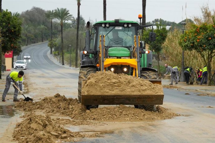 Archivo - Operarios retiran barro de una carretera en el municipio de Moguer. Imagen de archivo. 