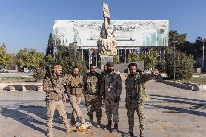 Archivo - Arquivo - Membros de grupos insurgentes armados posam após a derrubada de uma estátua do ex-presidente Hafez al-Assad na cidade de Aleppo, na Síria (arquivo).