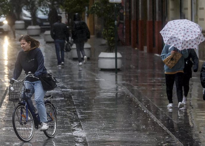 Archivo - Una persona sujeta un paraguas como consecuencia de la lluvia en una imagen de archivo