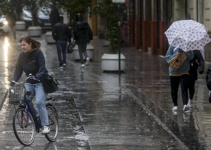 Archivo - Arxiu - Una persona subjecta un paraigua com a conseqüència de la pluja en una imatge d'arxiu