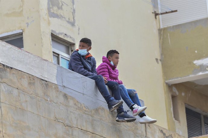 Archivo - Dos niños sentados sobre un muro en la nave de primera acogida del polígono del Tarajal, a 20 de mayo de 2021, en Ceuta (España). Durante los últimos tres días Ceuta ha recibido 8.000 ciudadanos marroquíes, de los cuales 5.600 ya han sido expuls