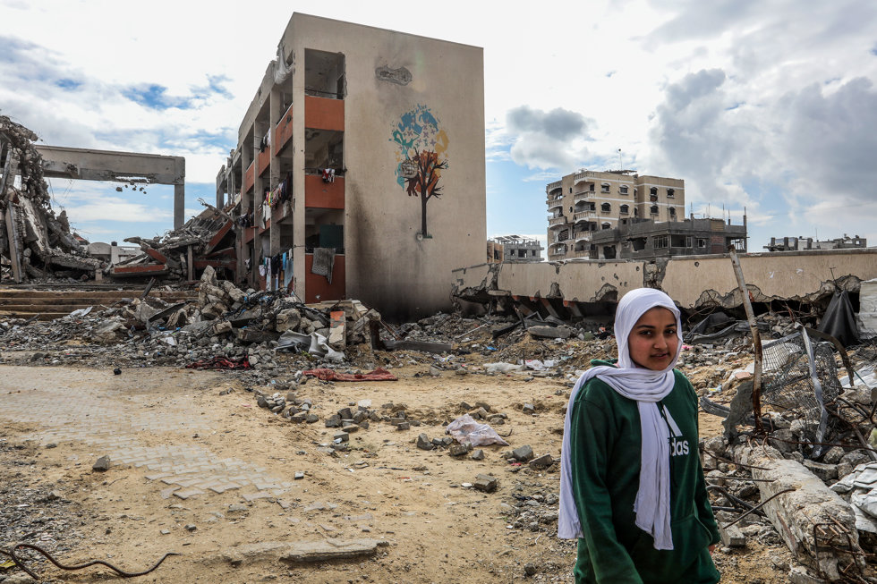 12 February 2025, Palestinian Territories, Khan Younis: A woman stands in front of a damaged building in Khan Younis, after the Israeli Forces withdrew as part of the ceasefire agreement with Hamas.