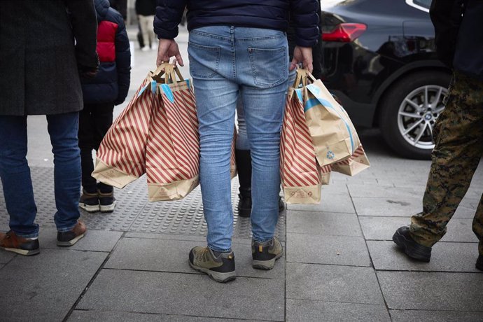 Archivo - Una persona con bolsas en una calle comercial