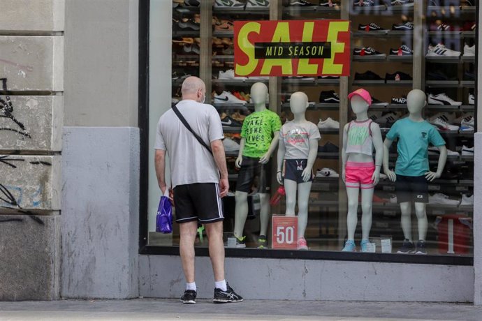Archivo - Un hombre mira el escaparate de una tienda