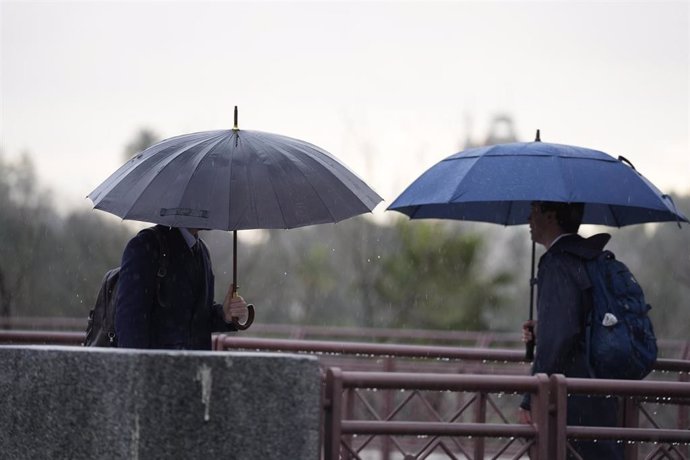 Varias personas se protegen de la lluvia con un paraguas.