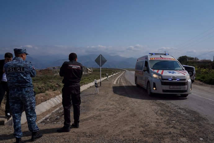 30 September 2023, Armenia, Kornidzor: Armenian police officers and officials stand on the roadside as an ambulance enters Kornidzor, Armenia.