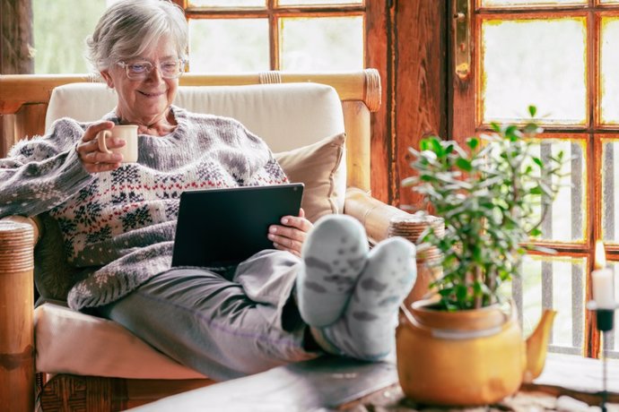 Archivo - Mujer mirando su tablet y tomando café/té. Descansas. Leer. Persona mayor