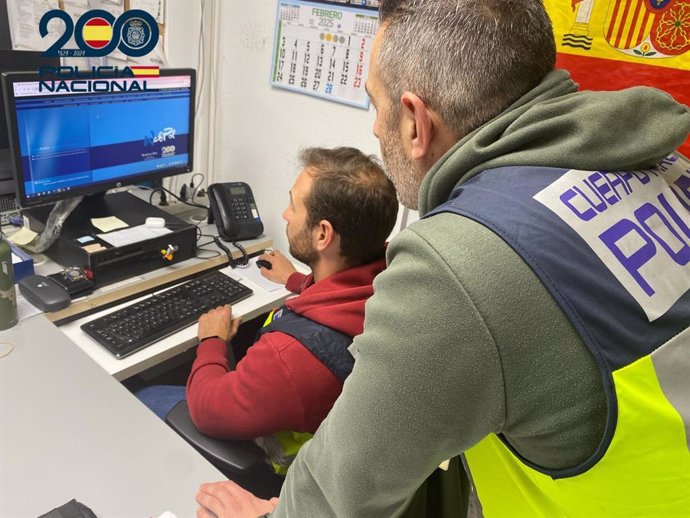 Imagen de recurso de dos agentes buscando información de un caso en el ordenador.