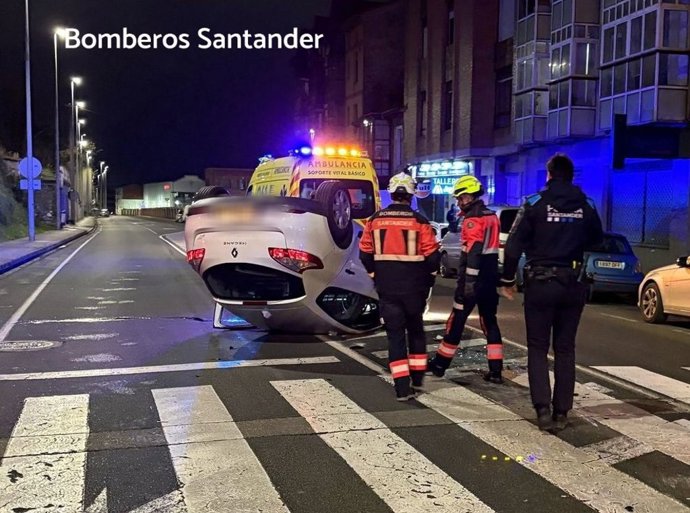 Coche accidentado que ha quedado volcado sobre la calzada en una calle de Santander