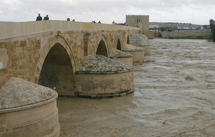 Archivo - Aspecto del Guadalquivir con una crecida a su paso por el Puente Romano de Córdoba, en una imagen de archivo.