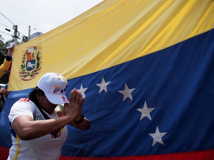 Archivo - Arquivo - 9 de janeiro de 2025, Lima, Lima, Peru: Mulher de joelhos rezando em frente a uma bandeira venezuelana quando centenas de venezuelanos, atendendo a um chamado mundial, saíram às ruas e se reuniram em frente à Embaixada da Venezuela em 