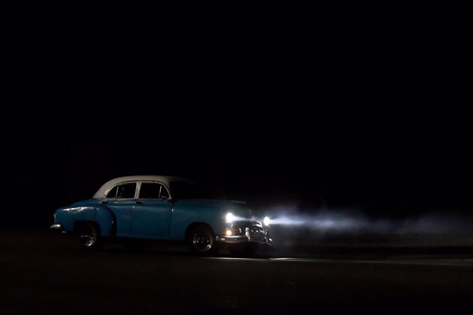 Archivo - Un coche antiguo circula por una avenida oscura tras un apagón en La Habana