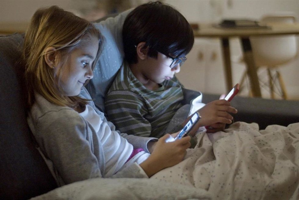 Archivo - Niños utilizando un 'smartphone'.